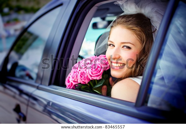 happy bride\
with flower bouquet siting in the\
car