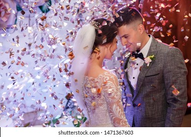 Happy bride and groom dancing under confetti at wedding reception. Wedding of beautiful caucasian couple, newlyweds dancing their first dance with special effects