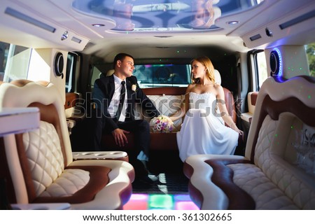 Happy bride and groom sitting in limousine