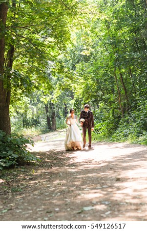 happy bride and groom walking in summer forest. Young wedding couple.