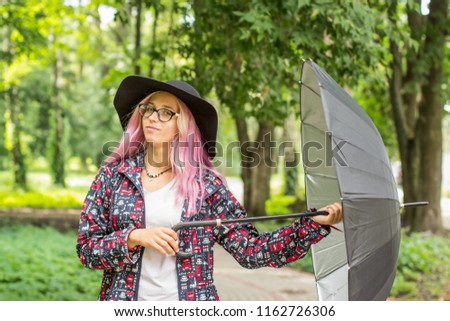 happy bright colorful autumn concept of smiling young teenager girl  playful and poses portrait with classic black hat and umbrella in unfocused blurred natural park environment space for walking