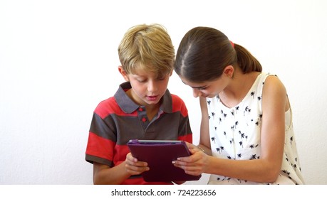 Happy Brother And Sister Playing On Tablet Device. Cute Kids Playing Games And Watching Cartoons On Tablet Computer. Having Fun