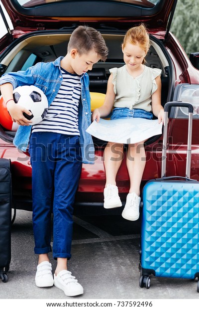 happy\
brother and sister in trunk of car going on\
trip