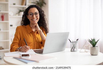 Happy Brunette Business Lady Using Laptop Smiling To Camera Posing Wearing Glasses Working Sitting At Workplace In Modern Office. Successful Entrepreneurship And Career Concept