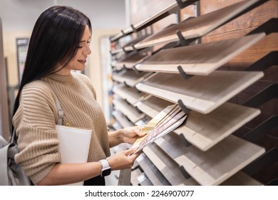 Happy brunette female interior designer choosing flooring tile color texture samples at store shop. Woman architect choice floor and wall finishing material for architecture and construction industry - Shutterstock ID 2246907077