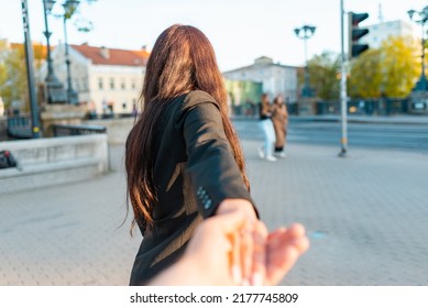 Happy Brunette Girl Turn Away Face Holding Boyfriend's Hand On A Street At Sunset On A Warm Spring,summer Evening.Follow-me Concept.Selective Focus.