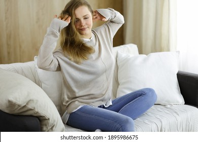 Happy brunette woman put hands behind head sitting leaned on couch european female enjoy lazy weekend or vacation in cozy living room, housewife relaxing feels satisfied after housework