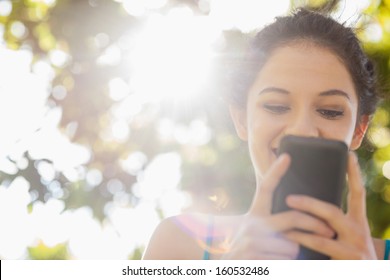 Happy brunette woman texting with her smartphone in a park - Powered by Shutterstock