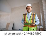 Happy building contractor with touchpad at construction site looking at camera. Copy space.