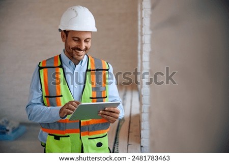 Happy building contractor using touchpad at construction site. Copy space.