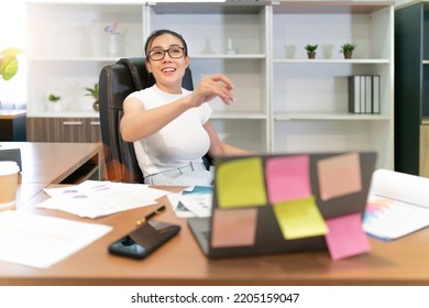 Happy Business Beautiful Asian Woman Work. Glasses Female Worker Busy With Online Group Meeting But Still Smiling And Cheerful. A Professional Confident Employee Having Team Video Call At Workplace.