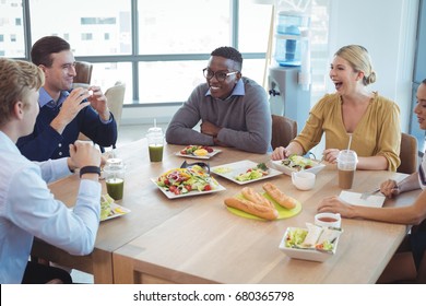 Happy Business Colleagues Having Lunch On Table At Office Cafeteria