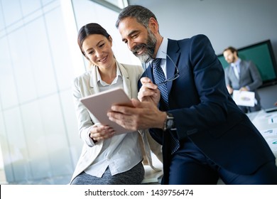Happy business colleagues in modern office using tablet