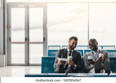 Happy Business Colleagues Waiting For Flight In Airport Lobby 