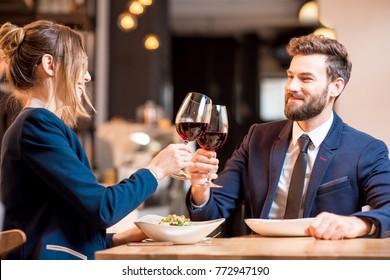 Happy business couple having a conversation during the dinner clinking glasses at the restaurant
