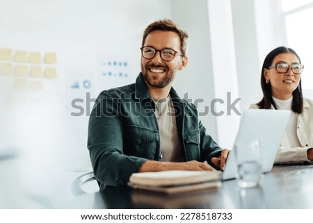 Happy business man listening to a discussion in an office boardroom. Business professional sitting in a meeting with his colleagues. Stock foto © 