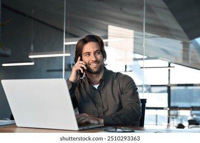 Happy business man merchant worker talking on cellphone working on laptop in office. Young smiling male sales client bank manager having conversation by mobile phone making call on cell at work. - Powered by Shutterstock