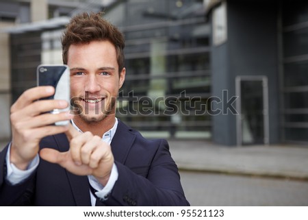Happy business man taking pictures with smartphone in city