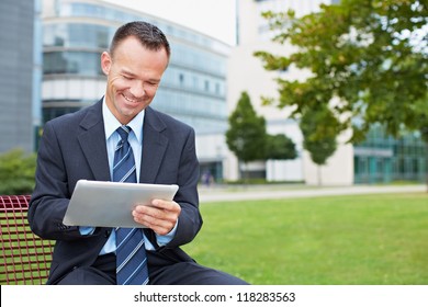 Happy Business Man Using Tablet PC Outside On A Park Bench