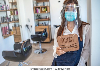 Happy business owner at a hairdressing studio hanging an OPEN sign during COVID-19. Local business in Europe reopening post pandemic. Portrait shot of a local business owner hanging an OPEN sign  - Powered by Shutterstock