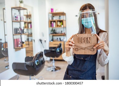 Happy business owner at a hairdressing studio hanging an open sign during COVID-19.  Local business in Europe reopening post pandemic. Portrait shot of a local business owner hanging an OPEN sign - Powered by Shutterstock