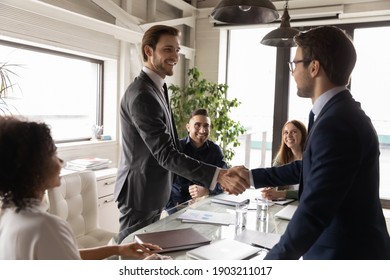 Happy Business Partners Shaking Hands At Corporate Meeting, Standing In Boardroom, Making Successful Deal, Agreement, Signing Contract, Smiling Executive Team Leader Greeting New Worker At Briefing