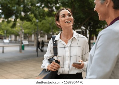 Happy Business People In Conversation At City Street With Copy Space. Two Mature Businesswomen Standing While Talking About Project. Successful Corporate Middle Aged Women Discussing Outside Office.