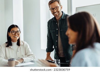 Happy business people discussing a project during a team meeting in a boardroom. Group of diverse young professionals brainstorming new ideas in an office. - Powered by Shutterstock