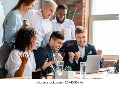 Happy Business People At Laptop Celebrating Success At Work Sitting In Modern Office. Successful Negotiations