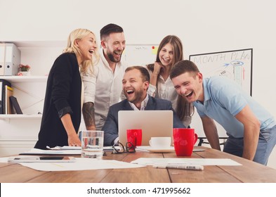 Happy business people laugh near laptop in the office. Successful corporate team of female and male coworkers joke and have fun together at work