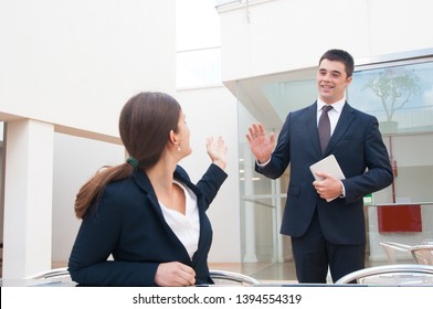 Happy business people meeting and greeting each other outdoors. Business woman sitting and man standing and waving his hand. Business people meeting concept.