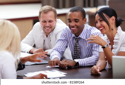 Happy Business People Sitting Around The Table At The Meeting