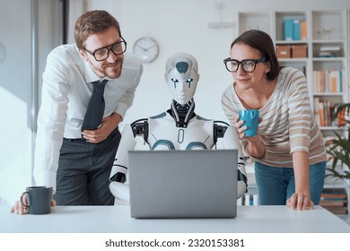 Happy business people supervising an AI robot working in the office - Shutterstock ID 2320153381