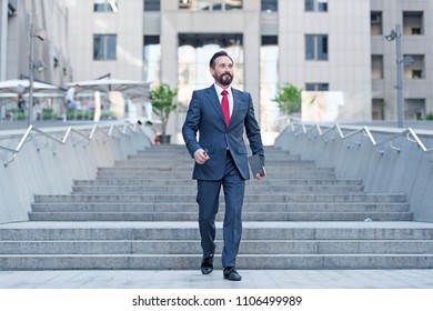 Happy Business Person Walks Downstairs In Hurry Movement With Tablet. Young Contemporary Businessman Walking Outdoor In The City ,with Ipad In Hand. Business, Work, Communication Concept.