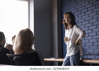 Happy business presenter woman talking to employees on meeting, joking, laughing, discussing creative ideas for project, brainstorming. Positive young coach giving presentation to colleagues - Powered by Shutterstock