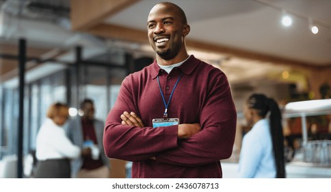 Happy business professional with a lanyard stands confidently with crossed arms in a modern office space, exuding professionalism and positivity amid busy colleagues in the background. - Powered by Shutterstock