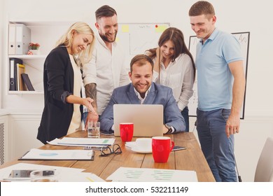 Happy business team, work result. People laugh near laptop in the office. Successful corporate group of female and male coworkers look at corporate internet site together at work