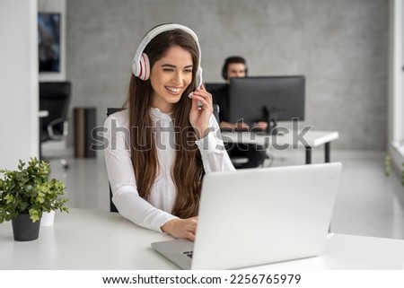 Happy business woman with headset working in call center. Young woman working as call center agent, holding microphone in hand.