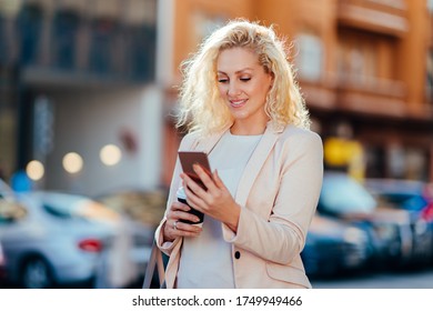 Happy business woman using smartphone on the street