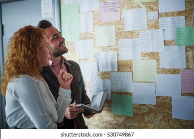 Happy businessman and businesswoman communicating near notice board and deciding when to conduct meeting for Board or Directors in office interior. - Powered by Shutterstock