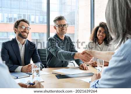 Happy businessman and businesswoman shaking hands at group board meeting. Professional business executive leaders making handshake agreement successful company trade partnership handshake concept.