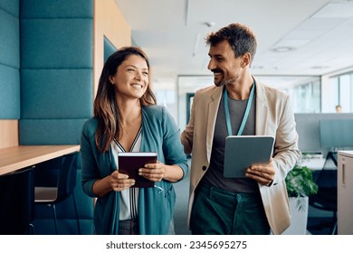 Happy businessman communicating with female colleague while walking through the office. - Powered by Shutterstock
