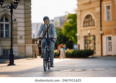 Happy businessman cycling while commuting to work by a bike. Copy space. - Powered by Shutterstock