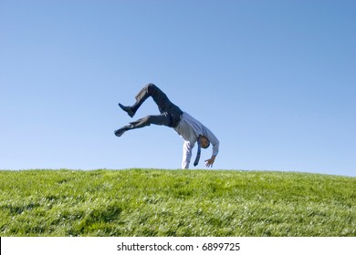 Happy Businessman Doing Somersault On Grass