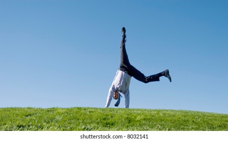 Happy Businessman Doing Summersault On Grass