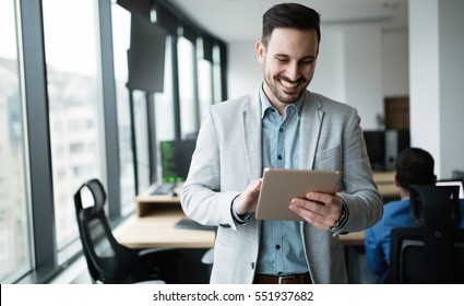 Happy businessman dressed in suit in modern office using tablet - Powered by Shutterstock