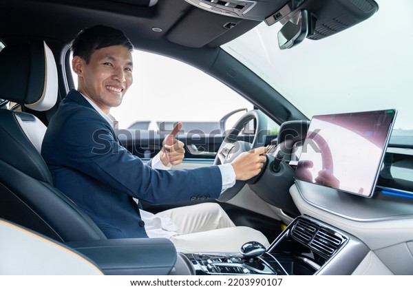 Happy\
businessman driving car before buying new electric vehicle with\
thumbs up. Electric car. EV Car. EV\
vehicle.