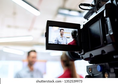 Happy businessman during corporate interview with female journalist. Manager answering question in office. Young woman at work as reporter with business man and cameraman shooting video for broadcast - Powered by Shutterstock