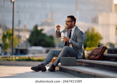 Happy businessman eating takeaway food while having lunch break in the city. Copy space. - Powered by Shutterstock