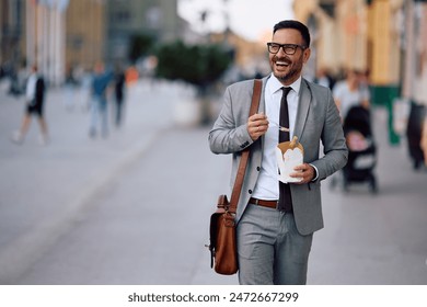 Happy businessman eating takeaway food during lunch break in the city. Copy space. - Powered by Shutterstock